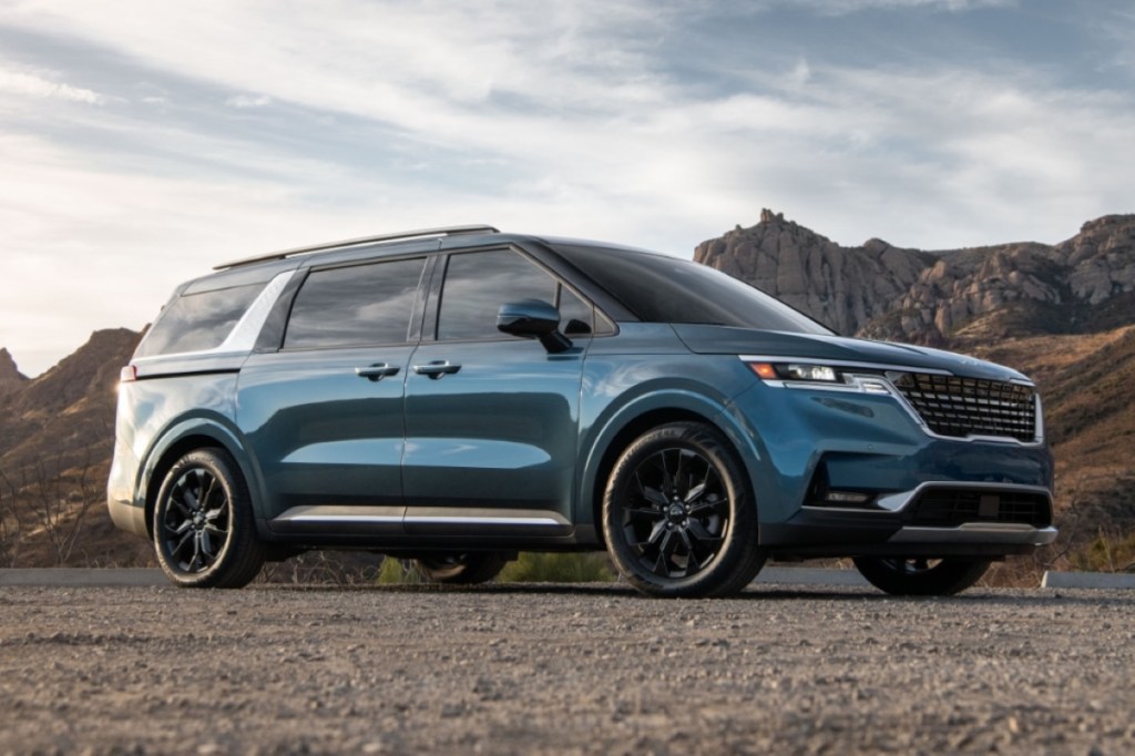 Blue 2022 Kia Carnival, save money on gas, with mountains in the background, there's a sliding door recall. 