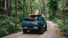 Blue Rivian R1T driving on a forest road