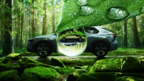 Blue-green 2023 Subaru Solterra EV parked in a forest