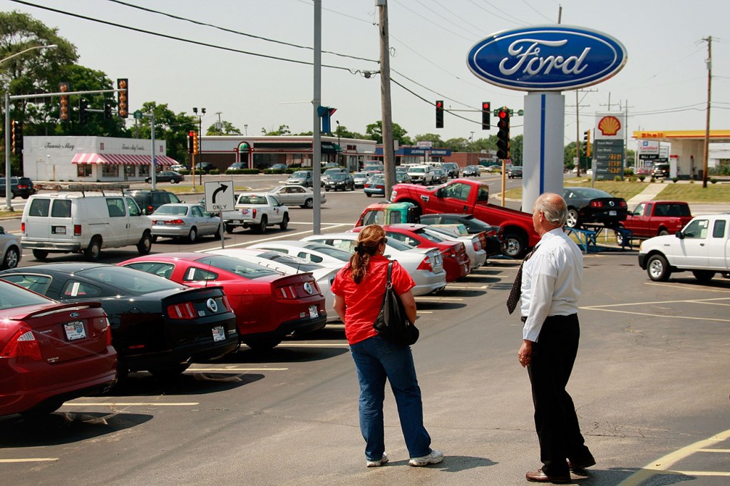 A man and woman standing in a Ford Dealership lot in 2009