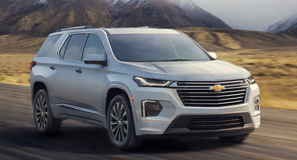 A gray Chevrolet Traverse is driving down the road. 