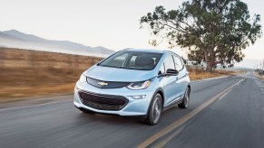 A 2017 Chevy bolt in light blue driving down a road toward the camera. GM recently announced an assembly plant would be closed for three weeks due to the nationwide Chevy Bolt recall