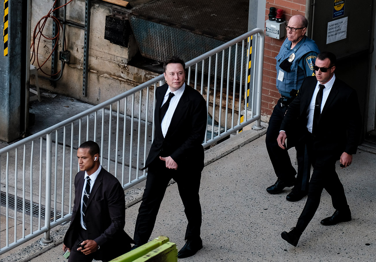 Elon Musk leaving a court room surrounded by security. Musk may be called as a witness in an upcoming Tesla crash trial