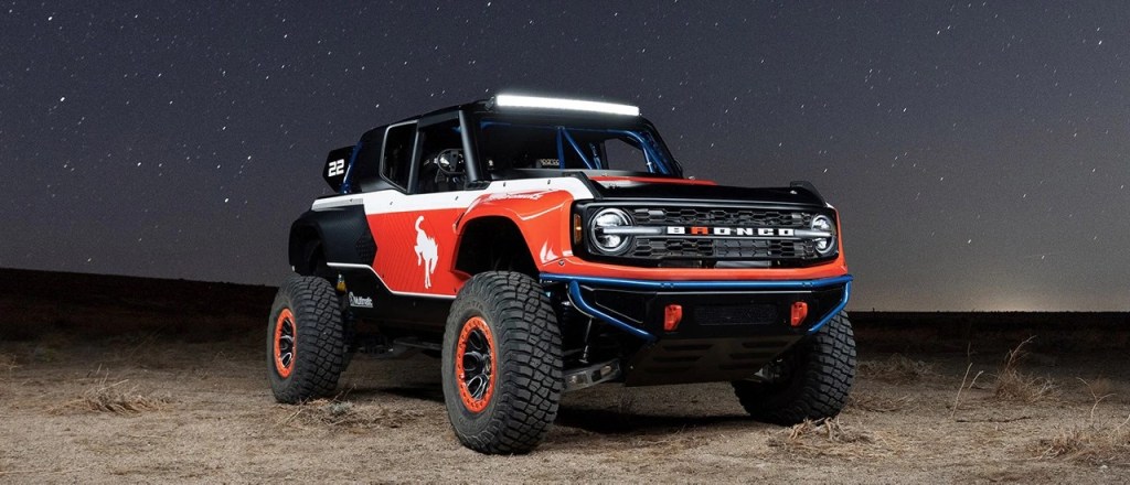 A red and black SEMA Show Ford Bronco Desert Racer parked in a desert at night.