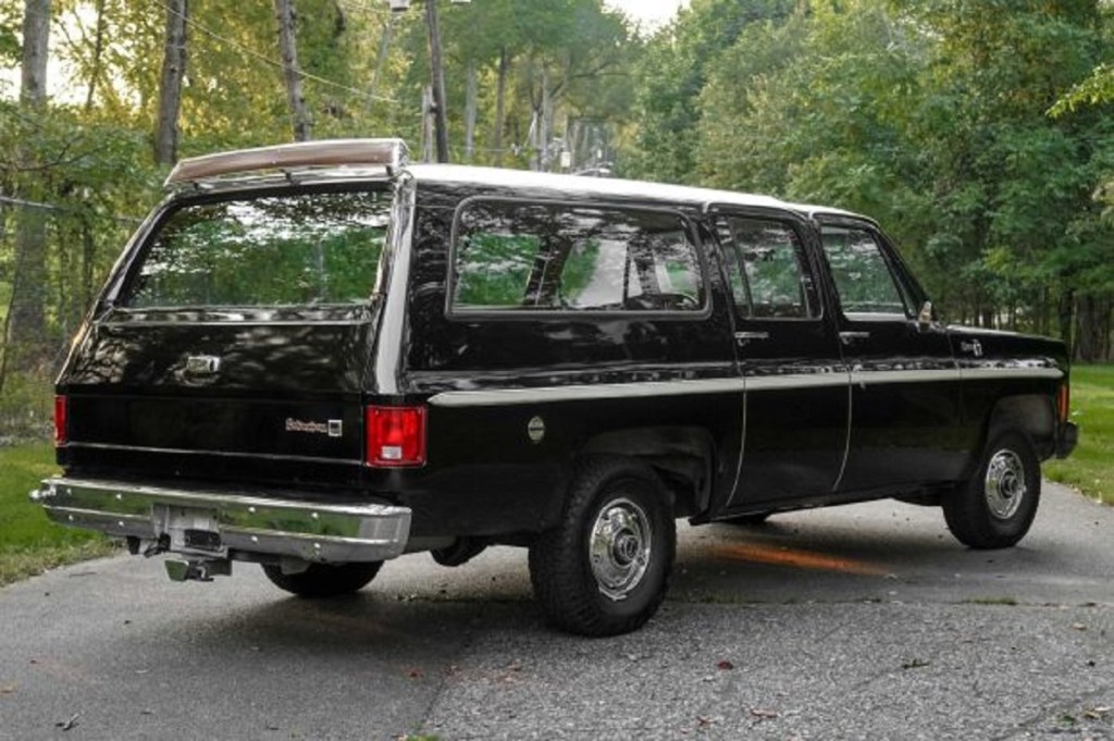 A black 1976 GMC Suburban Sierra parked outside.