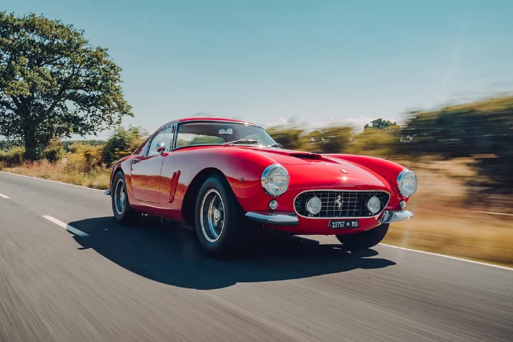 A red GTO Engineering Ferrari 250 GT SWB Revival driving down a country road