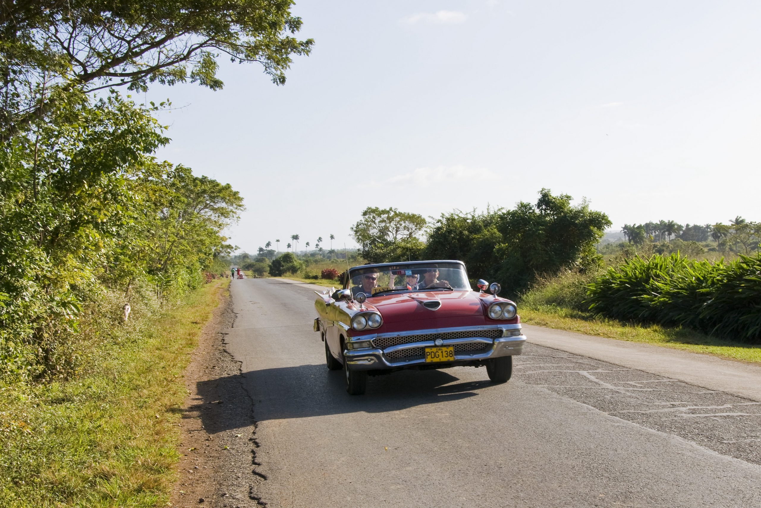 1958 Ford Fairlane, a beautiful classic car, driving down the road with the top down.