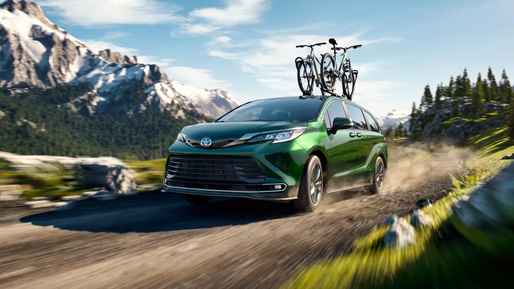 Green 2022 Toyota Sienna, save money on gas, driving on a mountainous road, it's one of the best commuter SUVs, according to KBB.