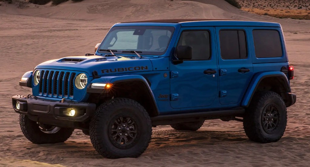 A blue Jeep Wrangler Rubicon is parked on the sand. 