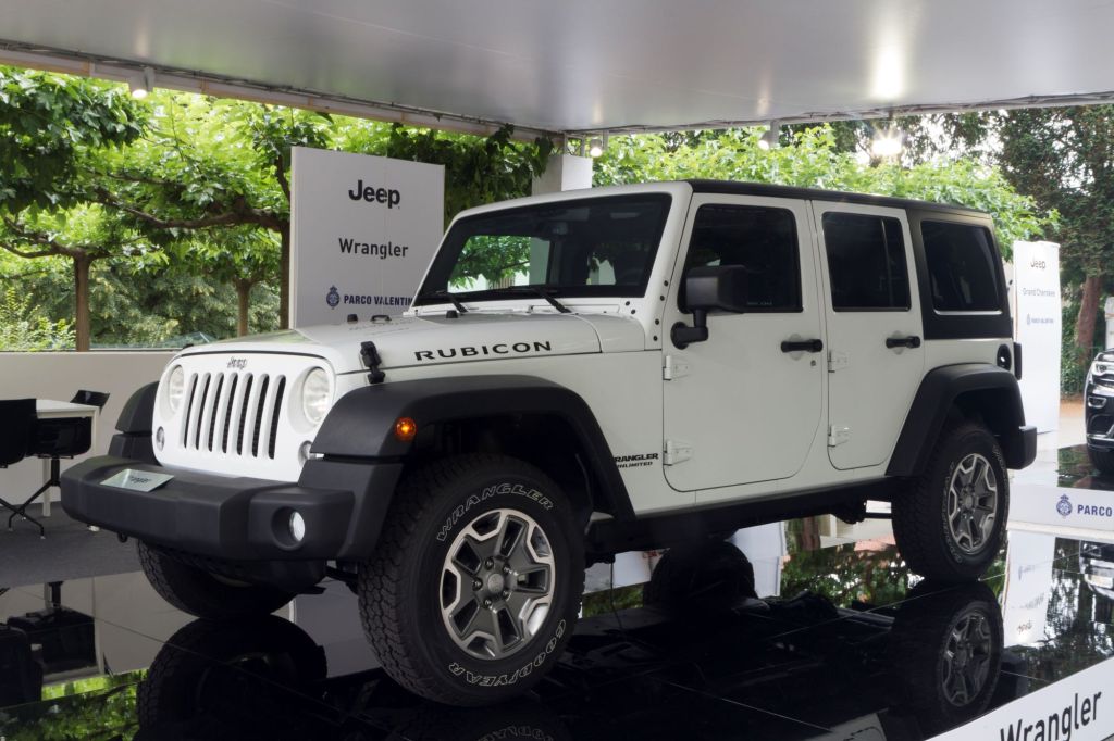A white Jeep Wrangler with a green tree background inside of a building.