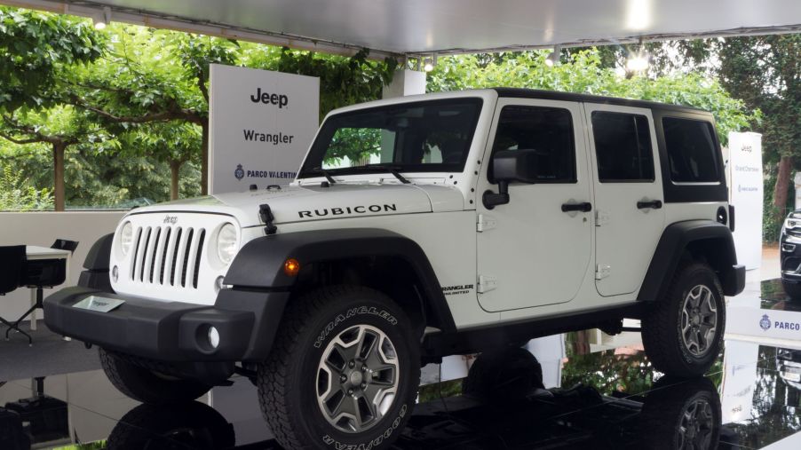 A white Jeep Wrangler with a green tree background inside of a building.