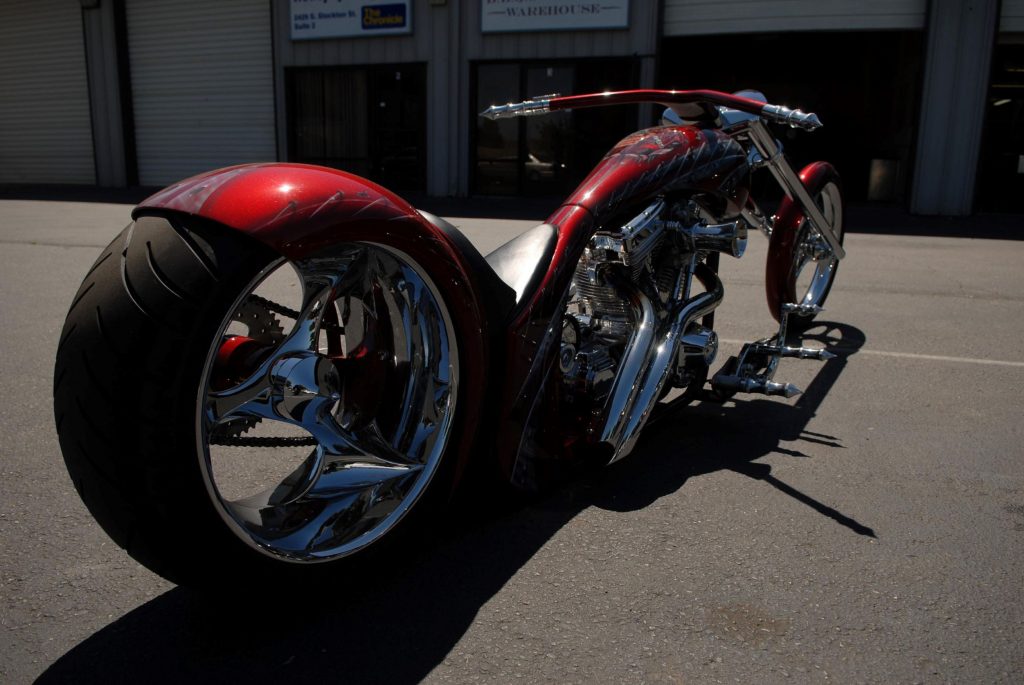 Jeff Nickells' custom red chopper motorcycle with a 70-degree rake in front of a garage