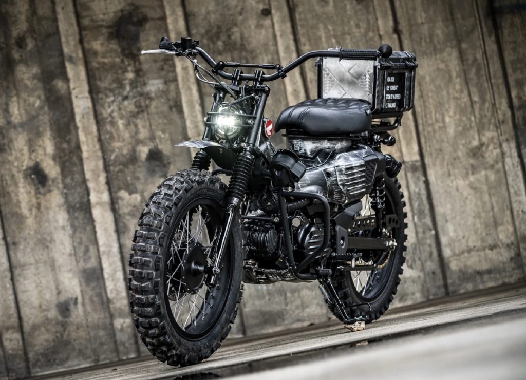 A black 2021 Honda Trail 125 Combat Custom K-Speed ​​by a wooden building
