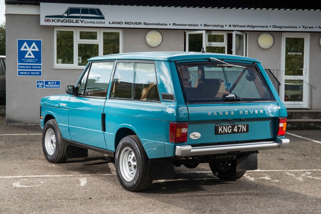 The rear 3/4 view of a turquoise Kingsley Cars KR Series 1992 Range Rover Classic in front of a building