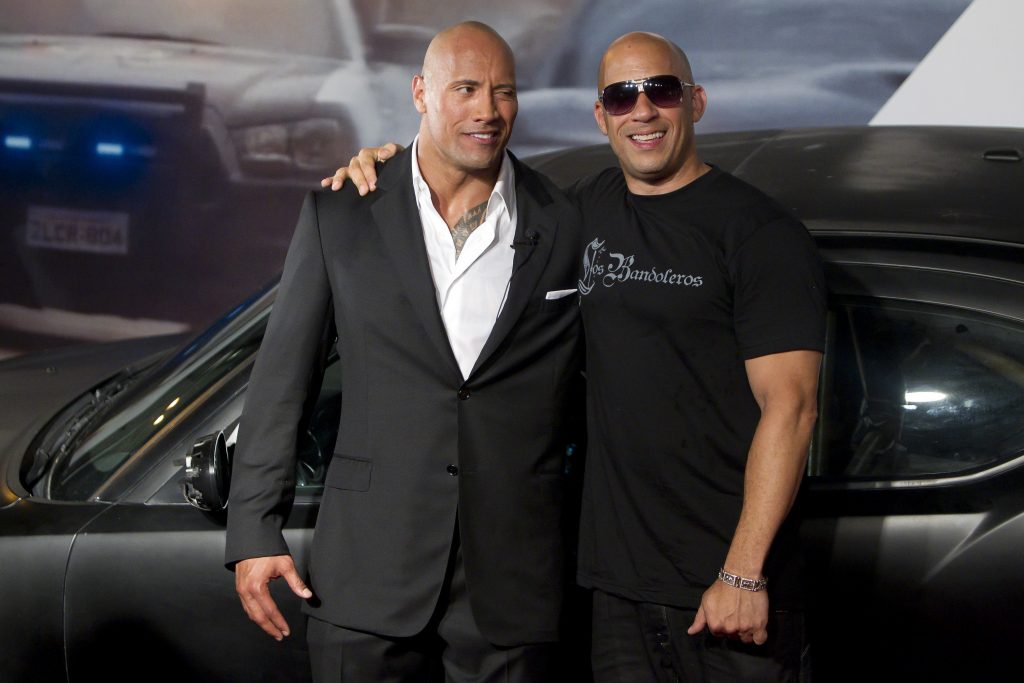 Dwayne "The Rock" Johnson and Vin Diesel standing in front of a car