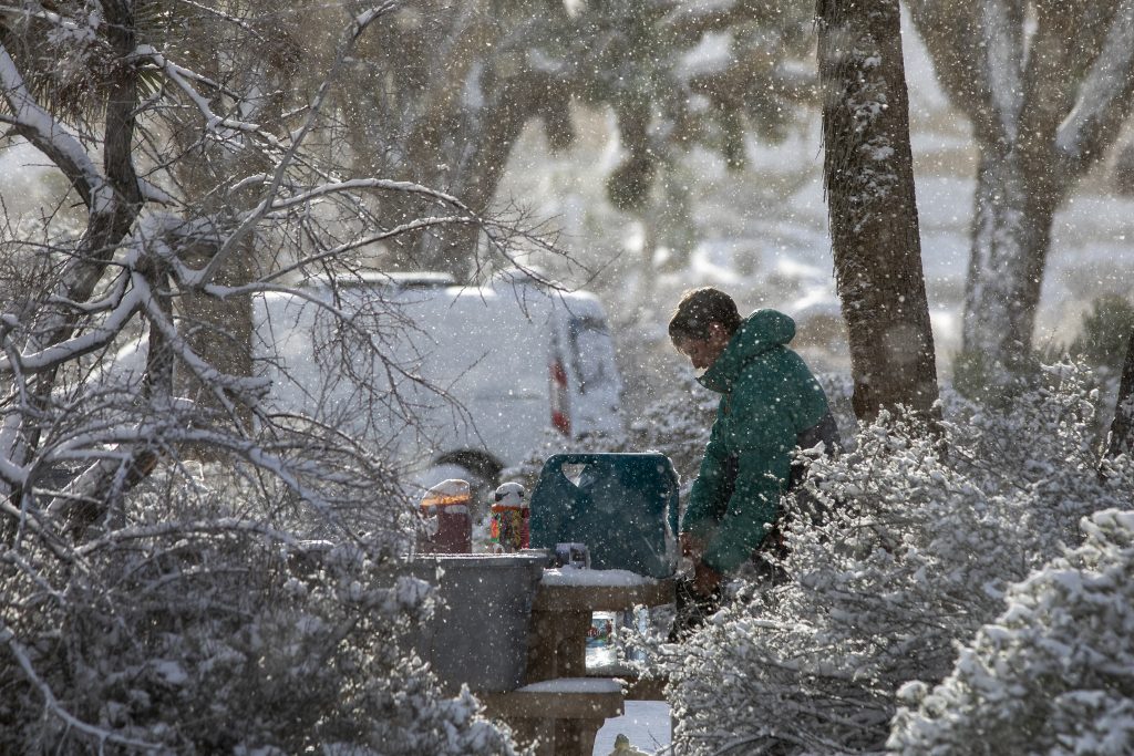 Man dressed in winter clothes standing next to a camper van