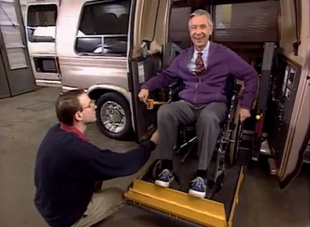 Mister Rogers sitting in a wheelchair in a Ford E-Series wheelchair van