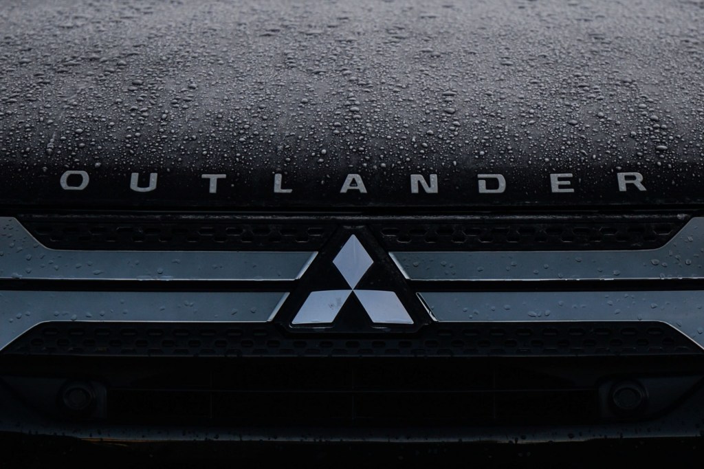 A Mitsubishi Outlander logo on a black background with raindrops.