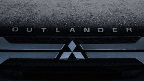 A Mitsubishi Outlander logo on a black background with raindrops.