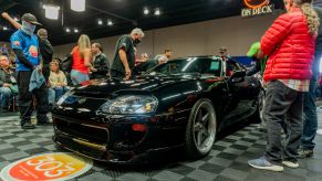 The front view of a black Modified 1994 Toyota Supra Mk4 Turbo in line at the 2021 Mecum Chicago auction surrounded by people
