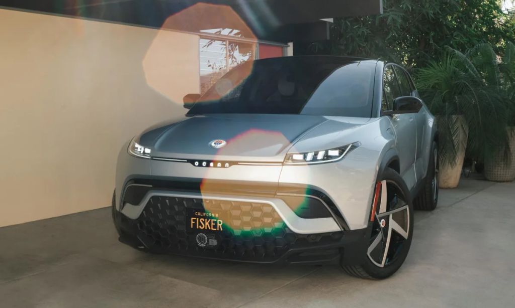 A silver 2023 Fisker Ocean parked outside of a house.