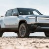 Passenger's side front angle view of silver Rivian R1T in a comparison between the Rivian R1S