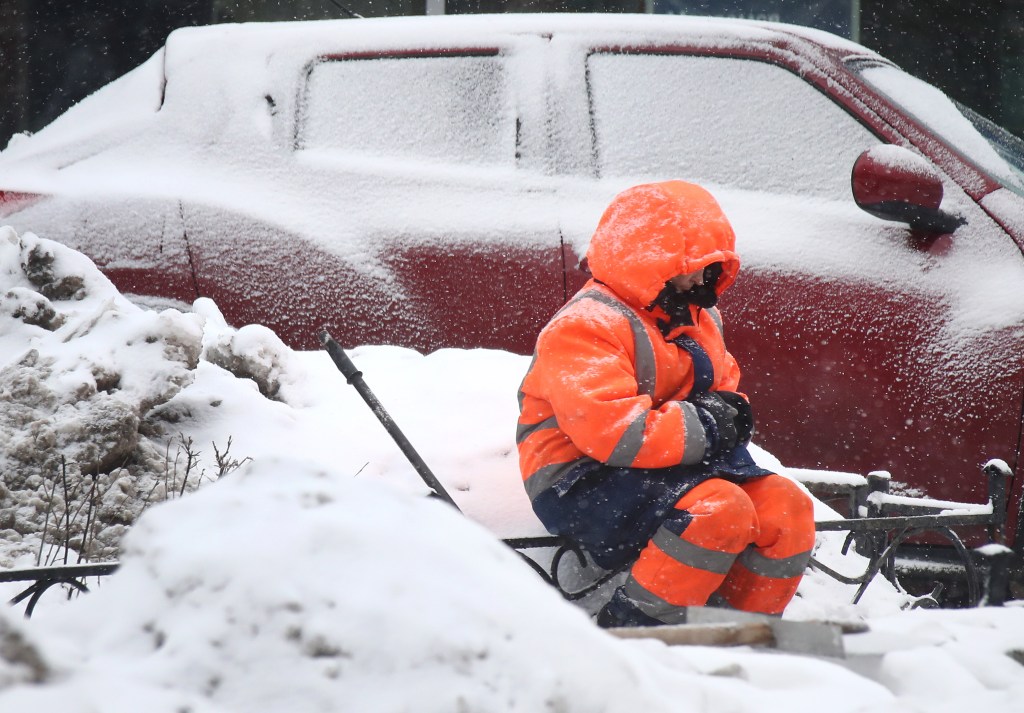 Person sitting beside car in heavy jacket