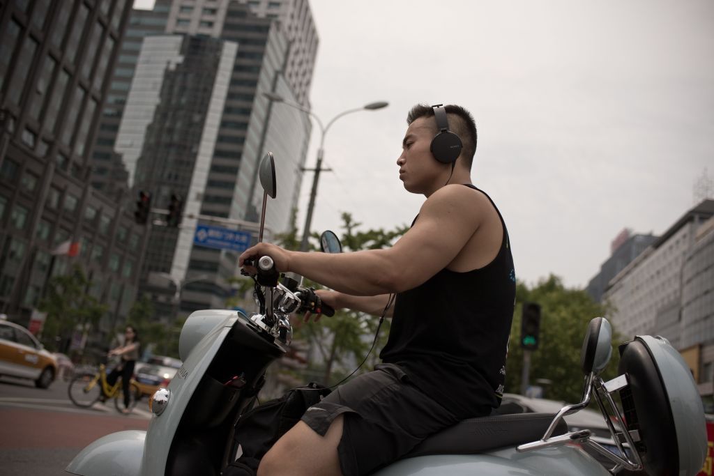 A person wearing headphones while driving a scooter, it could be illegal to wear headphones while driving in your area.
