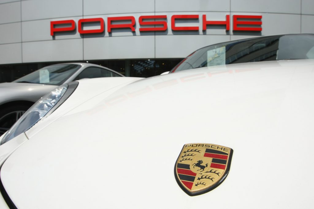 A Porsche emblem displayed in front of a dealer on a white car, could a three-row SUV be incoming?