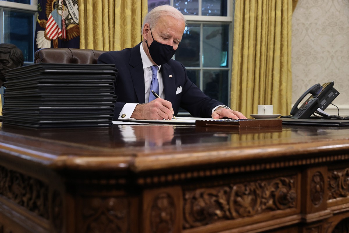 President Joe biding in the oval office signing a bill
