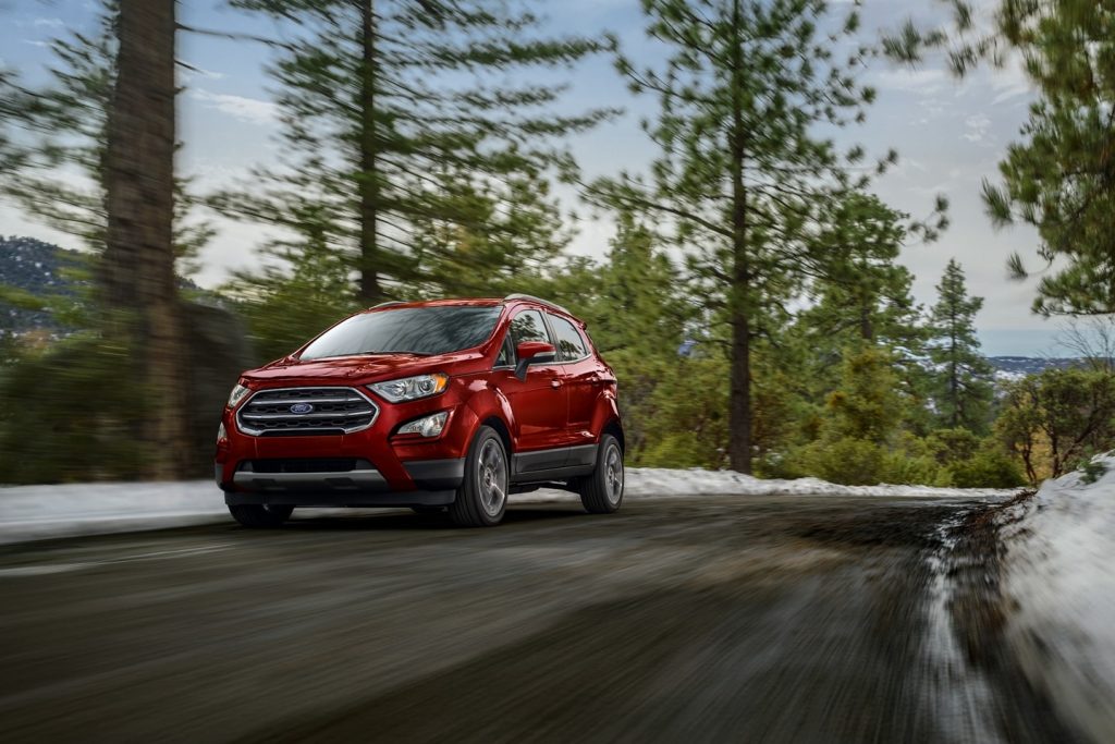 Red 2022 Ford EcoSport driving by a snowy forest