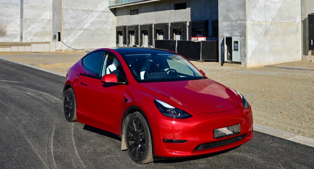 A red Tesla Model Y is parked outside a building.