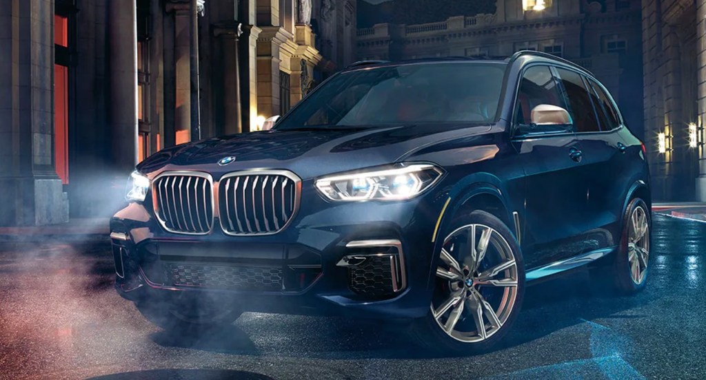A blue 2022 BMW X5 SUV is parked at night. 