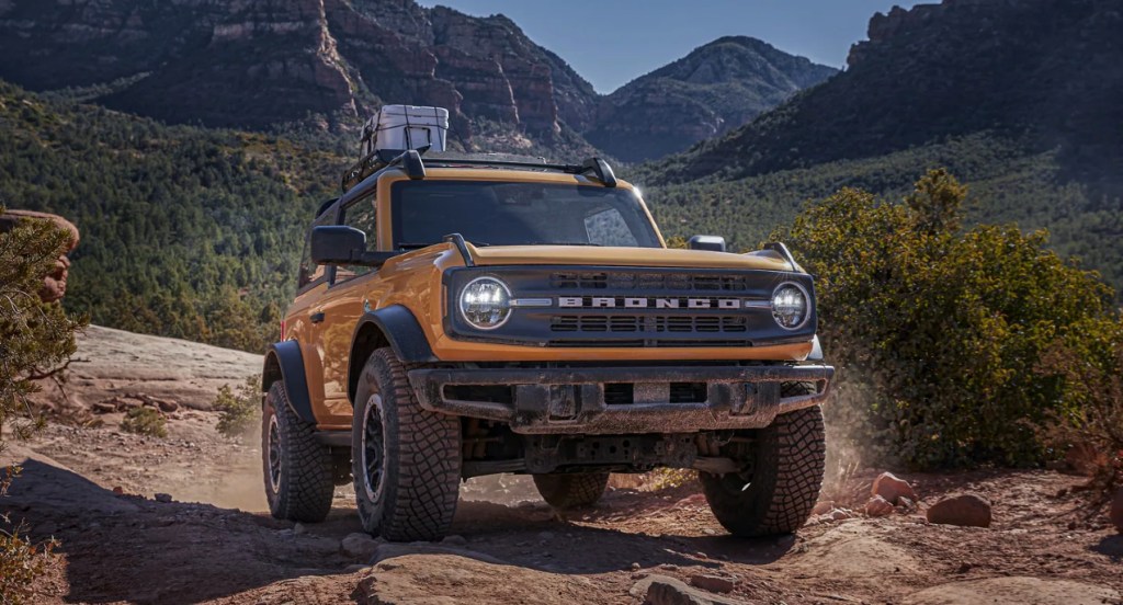 A yellow Ford Bronco off-road SUV drives along a dirt road, is the Wildtrak worth the extra money?