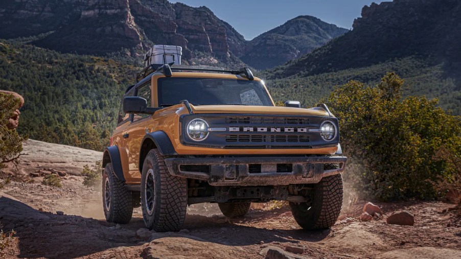 A yellow Ford Bronco off-road SUV drives along a dirt road, is the Wildtrak worth the extra money?