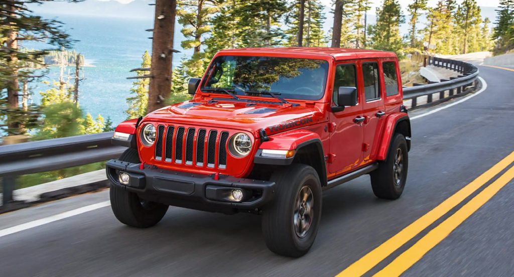 A red Jeep Wrangler is driving down the road. 