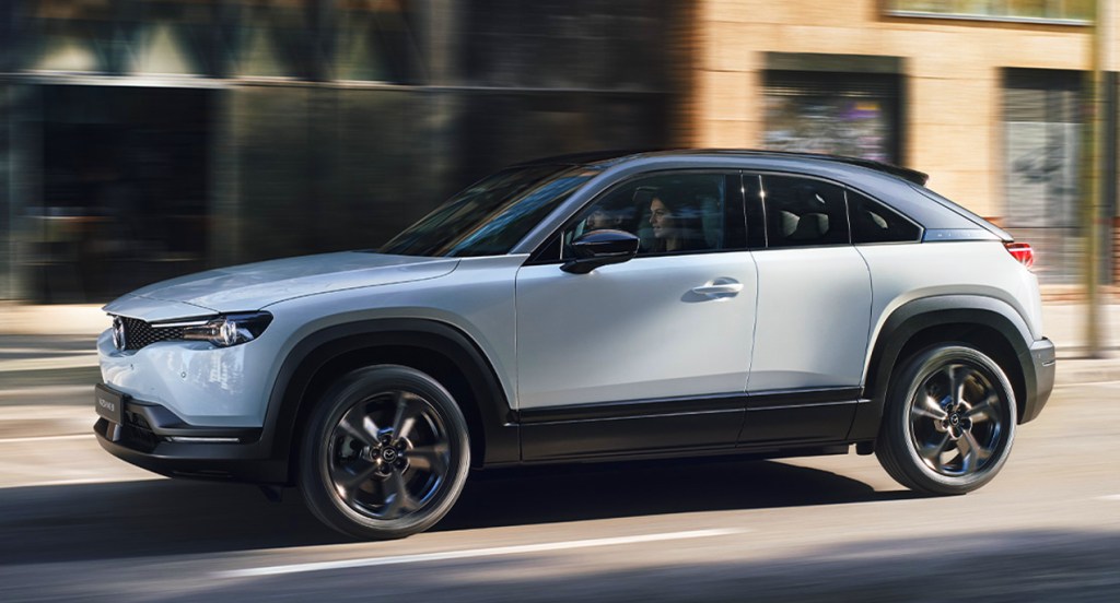 A gray 2022 Mazda MX-30 electric SUV is driving on the road. 