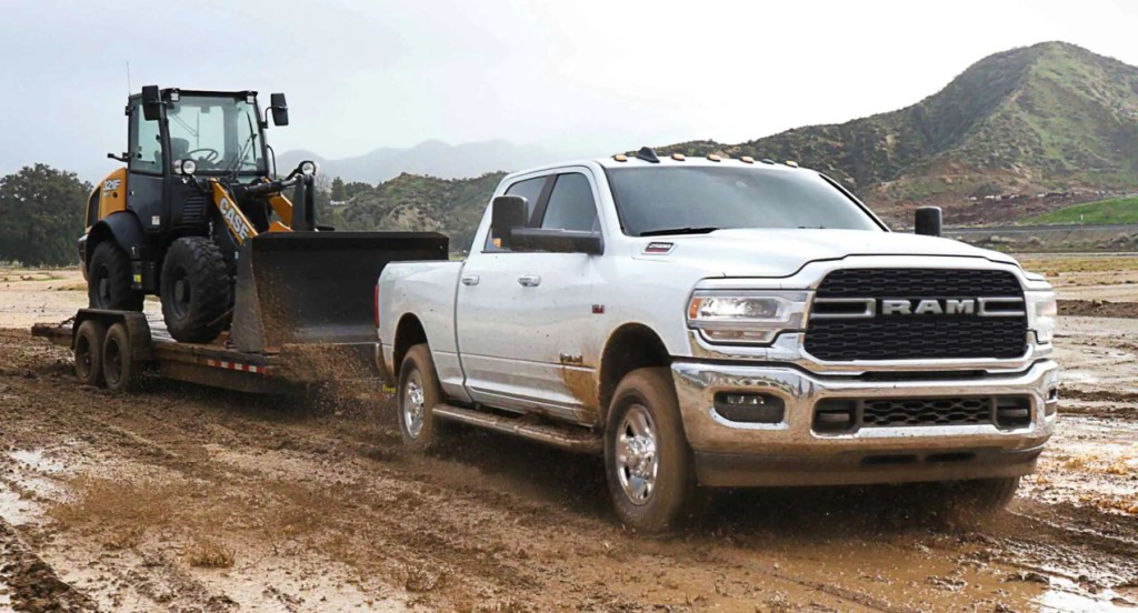 A white Ram 2500 is towing a small bulldozer with a trailer.