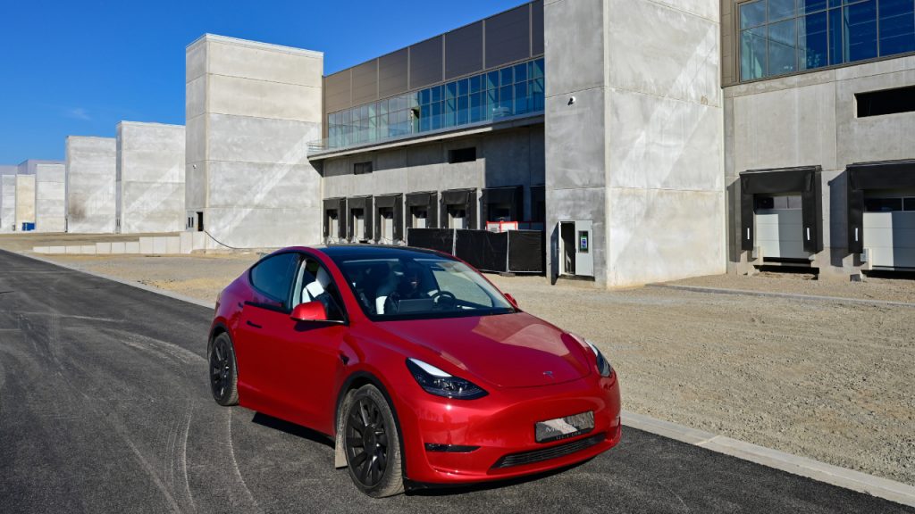 A red Tesla Model Y is parked outside.
