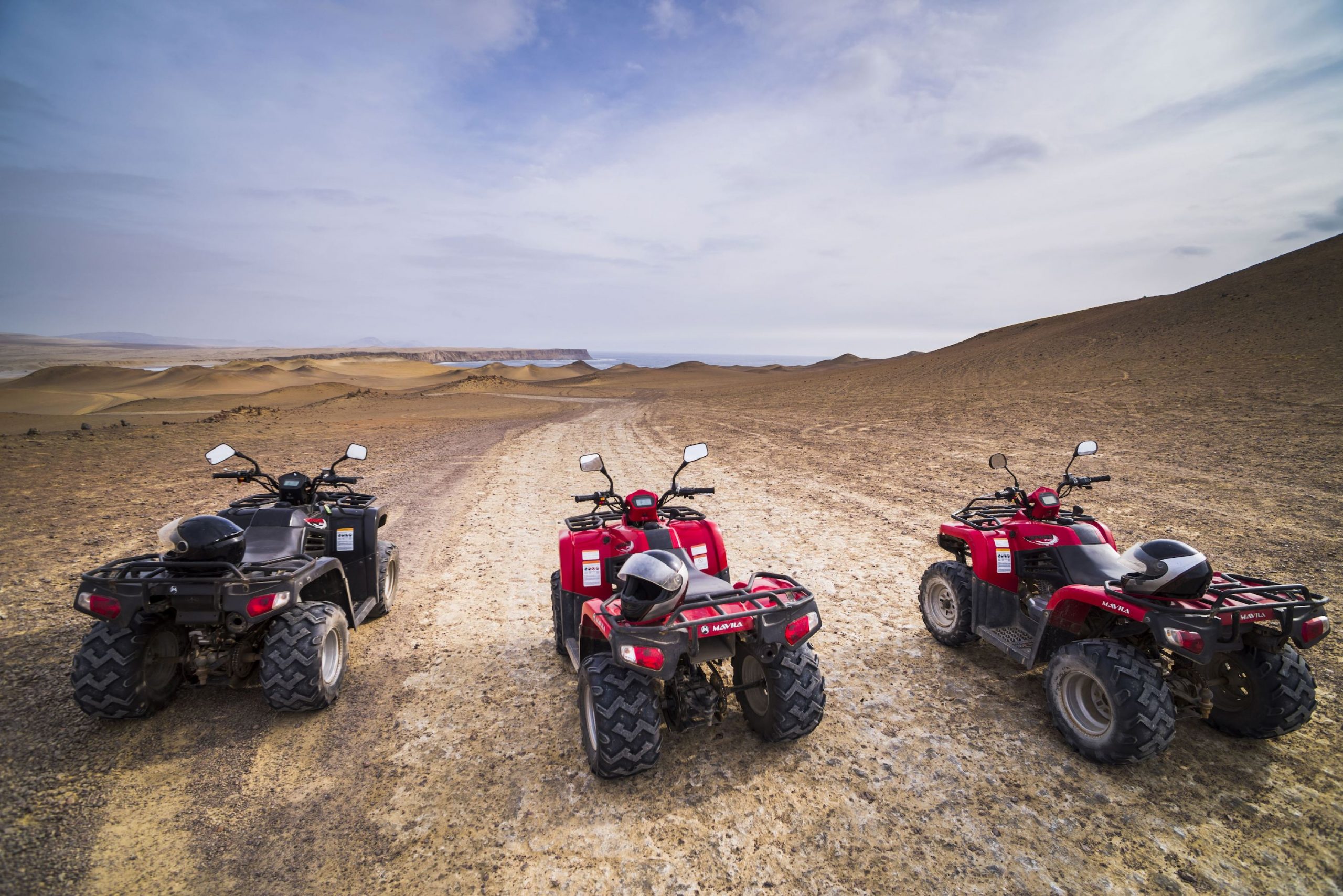 Three used ATVs parked in the desert.