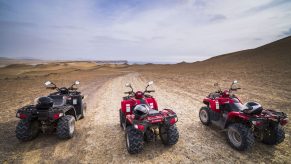 Three used ATVs parked in the desert.