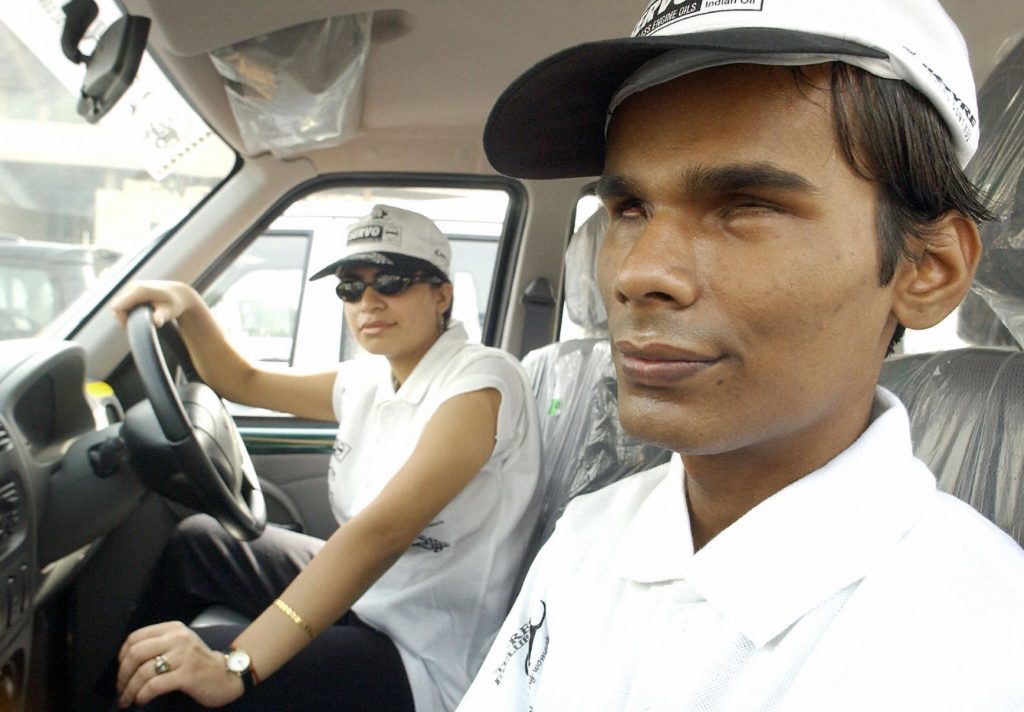 Visually impaired man riding in the passenger seat of a car in India 