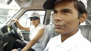 Visually impaired man riding in the passenger seat of a car in India