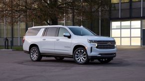 White 2022 Chevy Suburban, a good SUV for sleep, parked next to a large building
