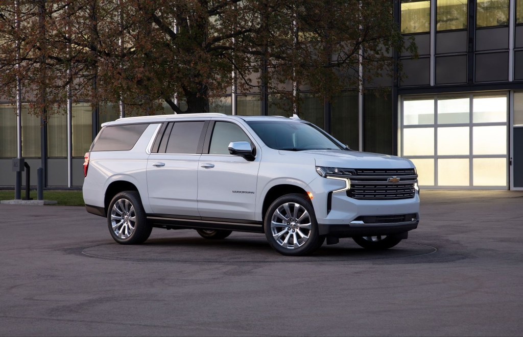 White 2022 Chevy Suburban, a good SUV for sleep, parked next to a large building