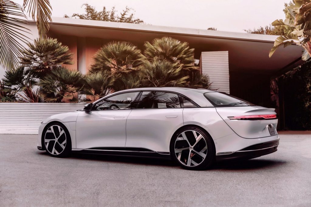 White 2022 Lucid Air, which has the longest EV driving range, parked near a modern house