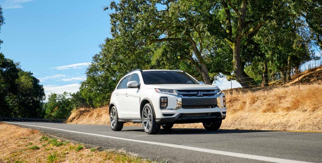 White 2022 Mitsubishi Outlander Sport driving on a country road