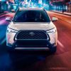White 2022 Toyota Corolla Cross driving on a city street at night