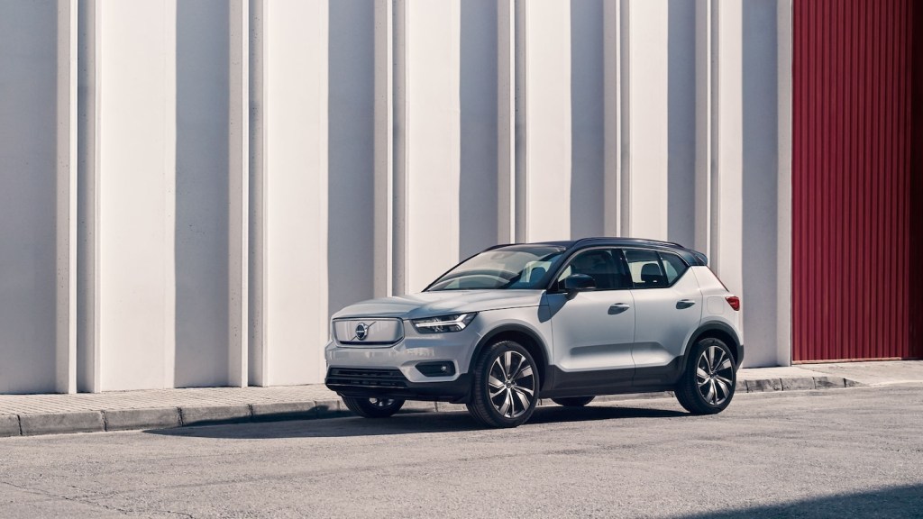 White 2022 Volvo XC40 Recharge compact SUV EV parked next to a large white and red building
