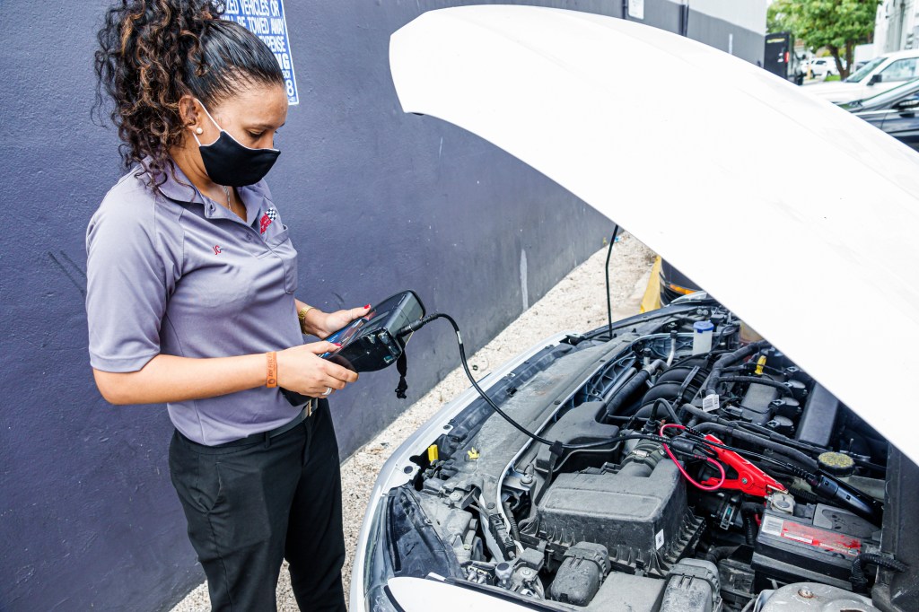 Woman testing and jump starting car battery